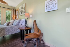 Una camera da letto con un letto, un comodino, una lampada, una sedia e una parete con una citazione incorniciata.