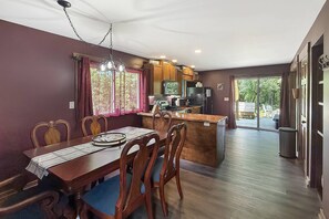 A dining area with a wooden table and chairs, a kitchen with wooden cabinets, and a view of the outdoors through a sliding glass door. - Free Ruby Falls Ticket & More-Hot Tub-Handcrafted Cabin with Tower-Lookout Mountain-Romantic Getaway (Lookout Mountain)