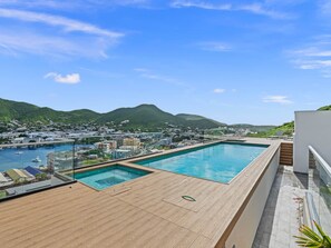 Ein Pool auf dem Dach mit Blick auf einen Hafen und Berge.