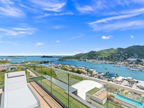 A high-rise hotel with a rooftop pool and a view of a marina and mountains. - C303 - Beautiful 1 Bedroom with Terrace (Cole Bay)