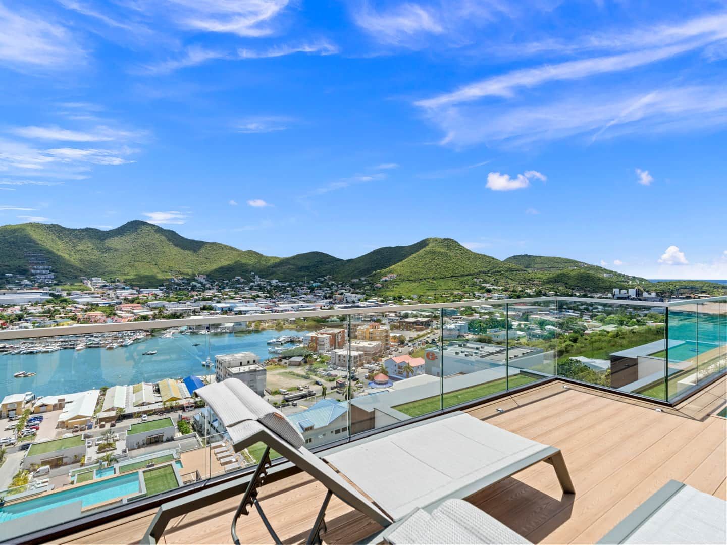 A high-rise hotel with a panoramic view of a marina and mountains.