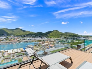 A high-rise hotel with a panoramic view of a marina and mountains. - C303 - Beautiful 1 Bedroom with Terrace (Cole Bay)
