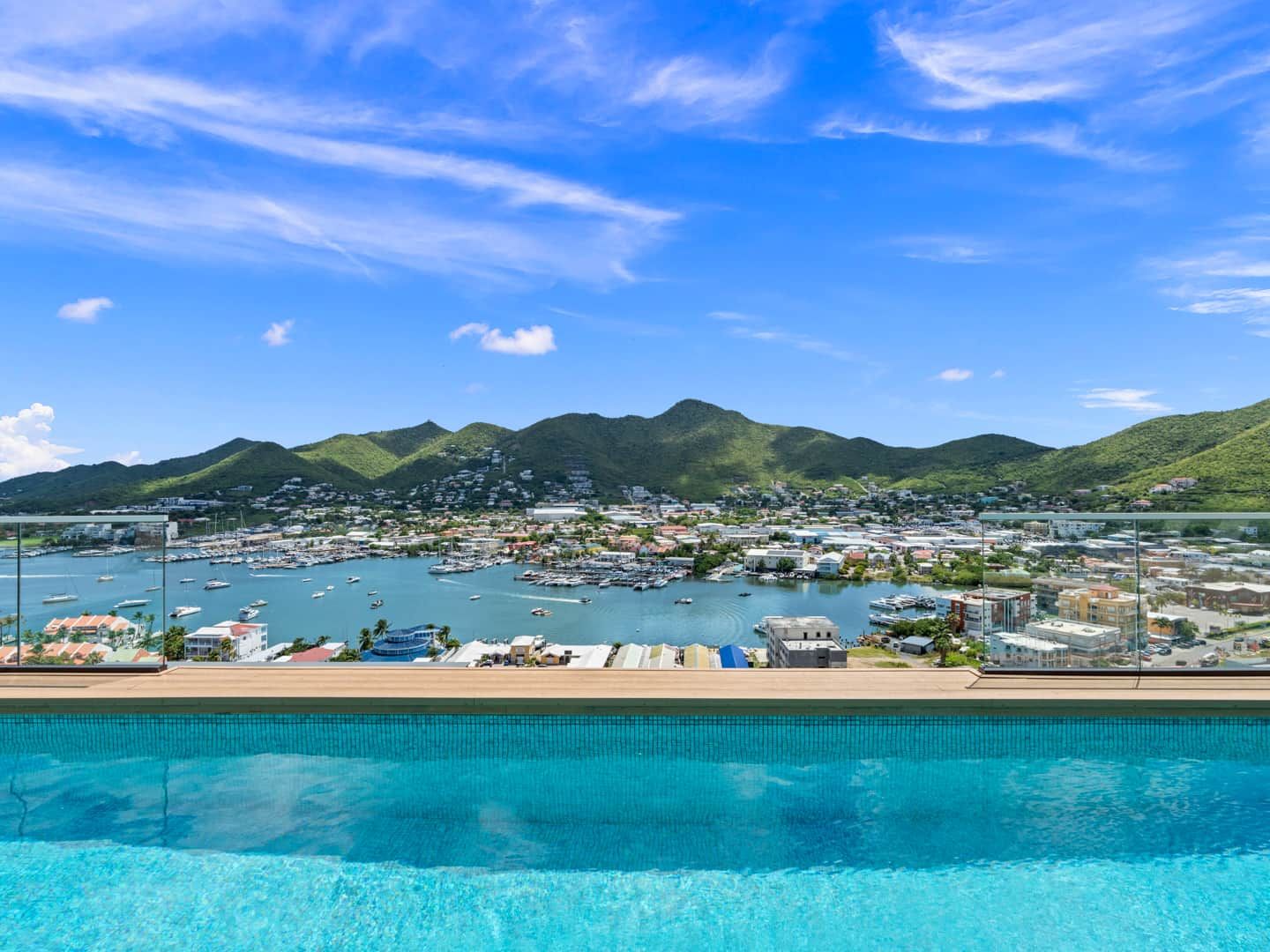Une ville côtière dotée d’un port de plaisance, d’une eau d’un bleu limpide et de montagnes en toile de fond.