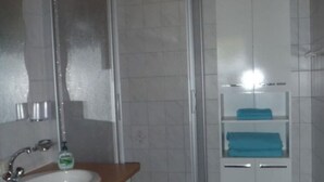 Un baño con ducha, lavamanos y armarios de almacenamiento.