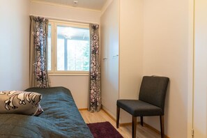 A bedroom with a bed, a chair, and a window with curtains. - Diverse outdoor activities, incl. end cleaning (Rukatunturi)