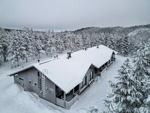 A large, modern building with a flat roof, surrounded by snow-covered trees. - Diverse outdoor activities, incl. end cleaning (Rukatunturi)