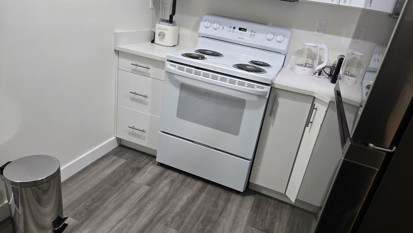 Una cocina con estufa, horno y cafetera sobre la encimera.