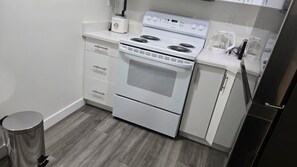 A kitchen with a white stove, oven, and a coffee maker on the countertop.