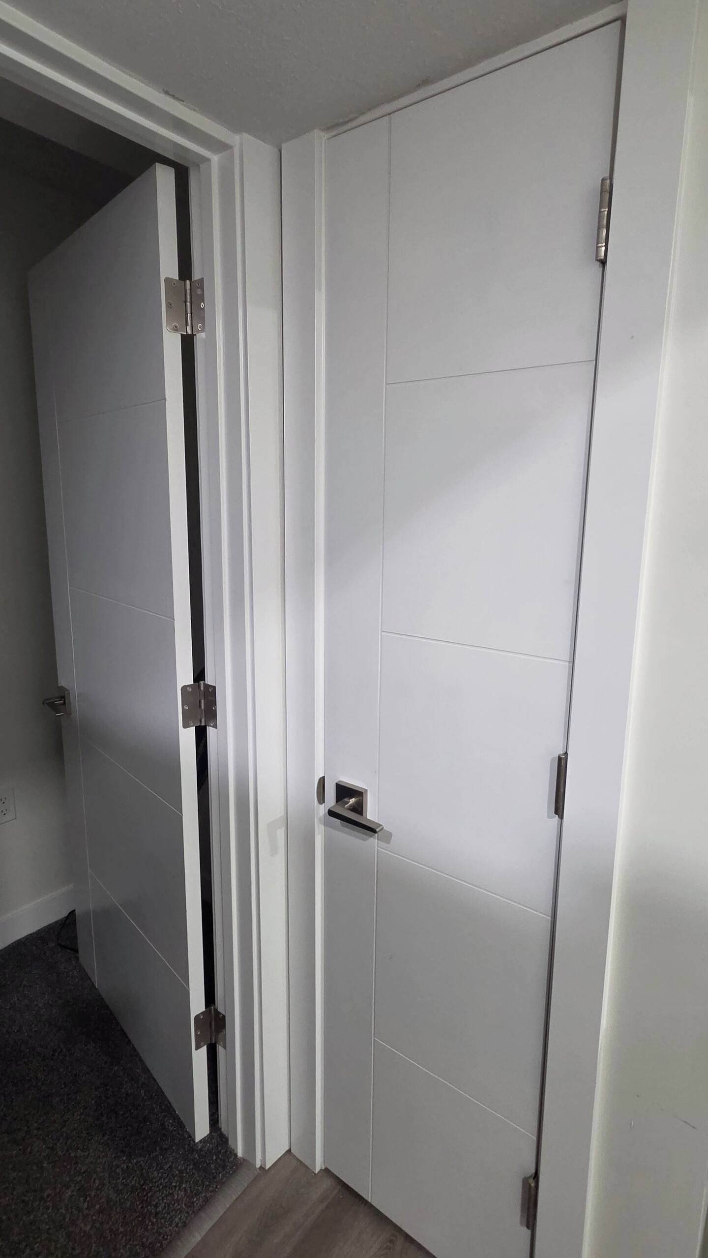 Une pièce dont la porte est fermée, avec une poignée de porte visible, et où l’on aperçoit une partie d’un sol recouvert de moquette.