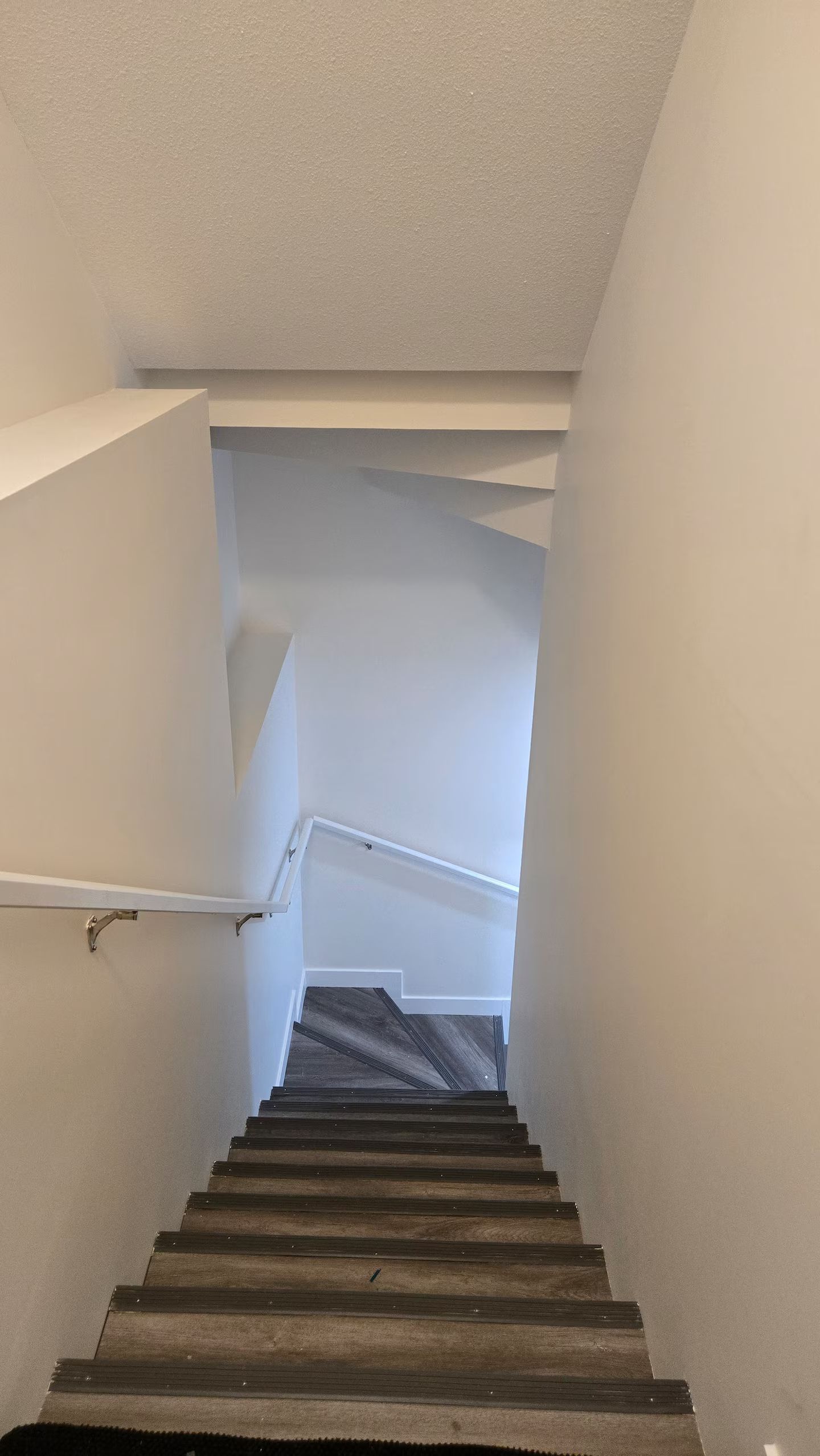 A staircase with a handrail and a dark wooden finish.