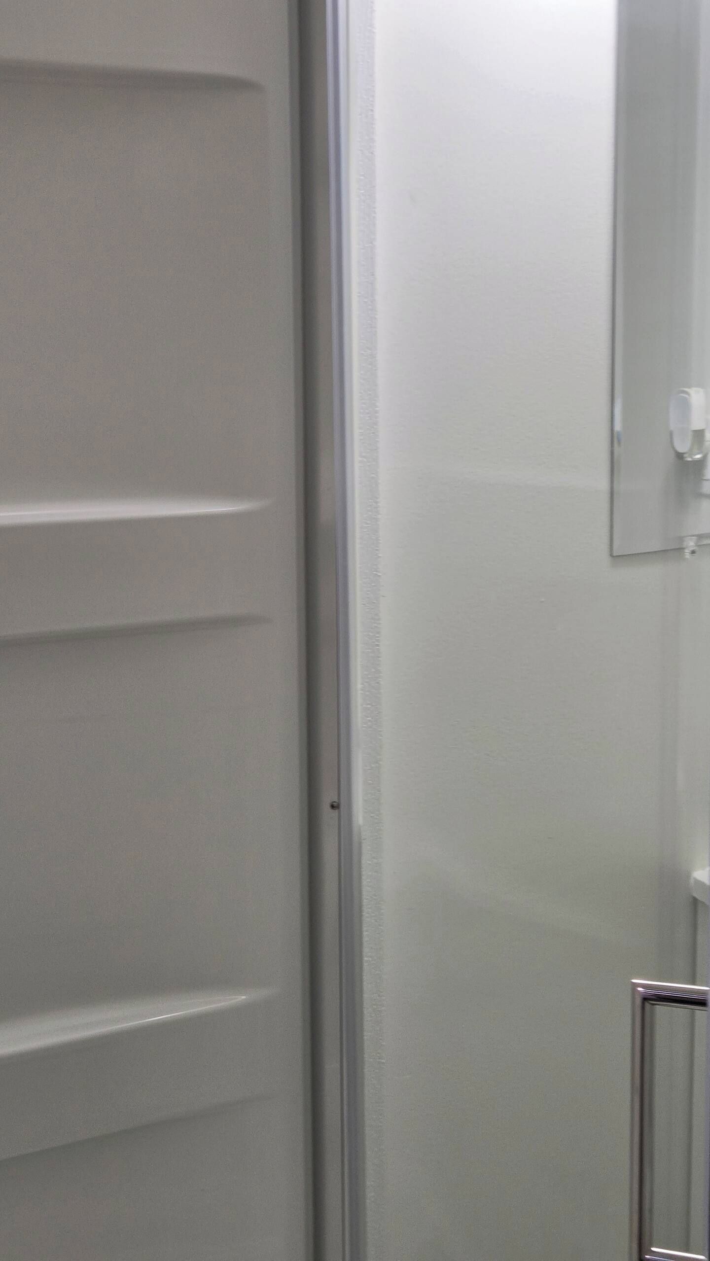 A white door with a metallic handle and a white wall with a light switch.