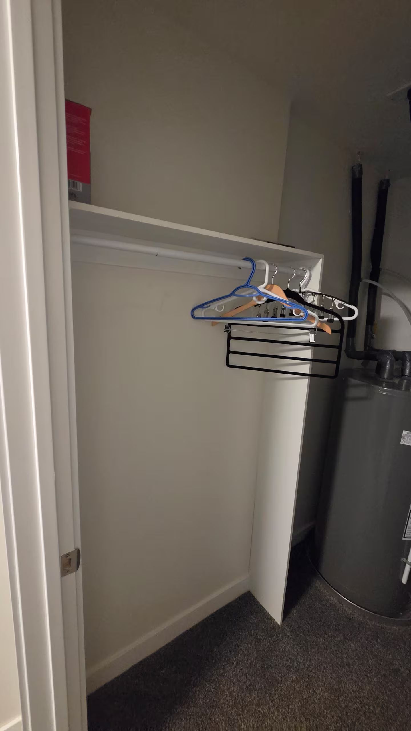 Ein kleines Zimmer mit integriertem Wäschetrockner, einer weißen Tür und einem Warmwasserbereiter.