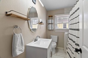 A bathroom with a white sink, mirror, and toilet. There is a towel rack with a towel hanging on it. - The House Gabriel Visited (Rockport)