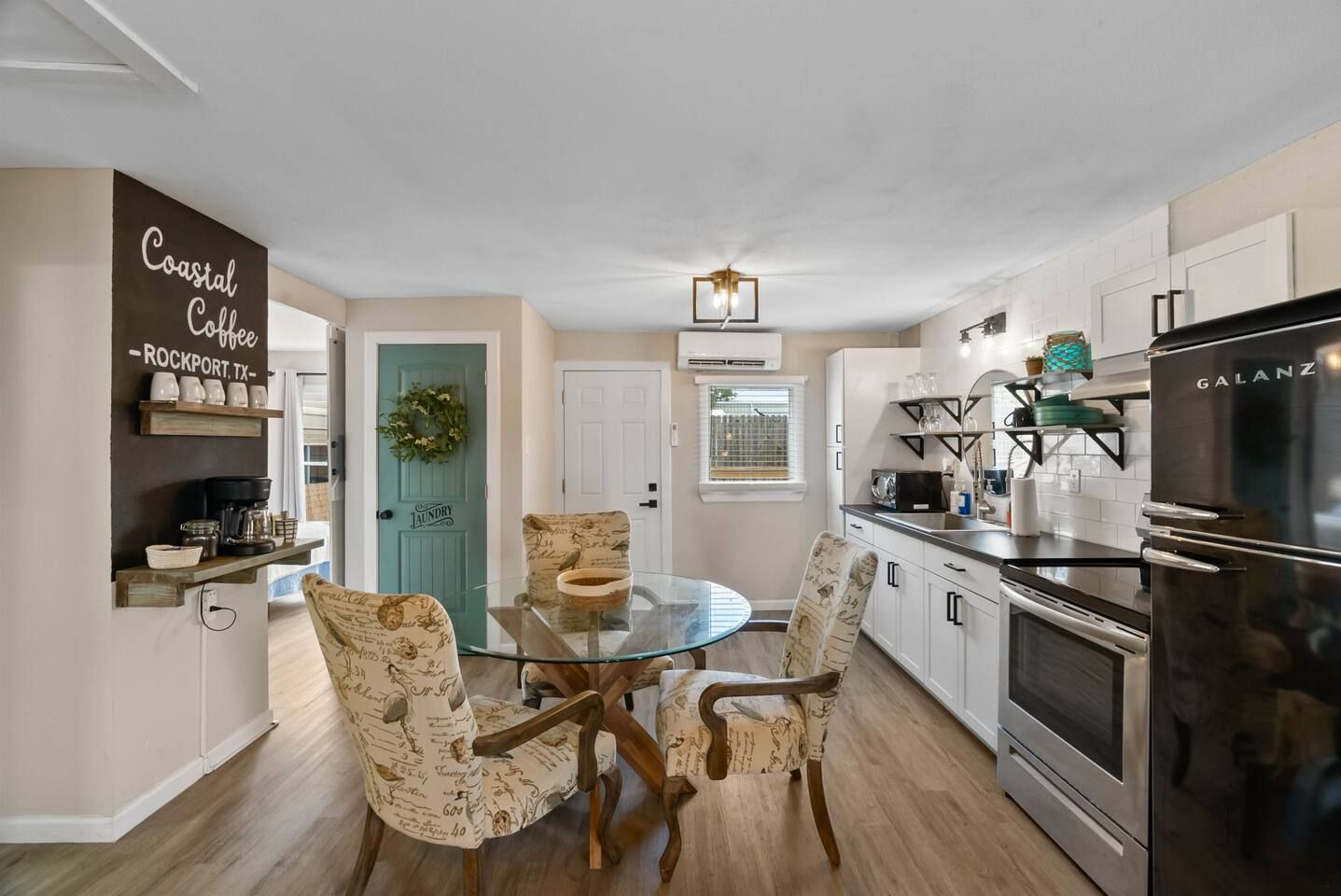 A modern kitchen with a Galanz refrigerator, a coffee station, and a dining area with patterned chairs.