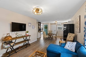 A modern living room with a sofa, a TV, and a dining area with chairs and a table. - The House Gabriel Visited (Rockport)