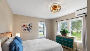 Quarto com cama, penteadeira, janela e luminária no teto.