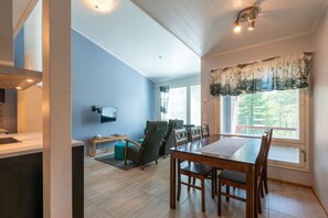 A modern living room with a dining area, a flat-screen TV mounted on the wall, and a large window with curtains. - Activities from the front door, incl. cleaning (Rukatunturi)