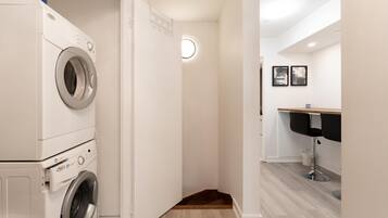 A laundry room with stacked washing machines and a small sink area.