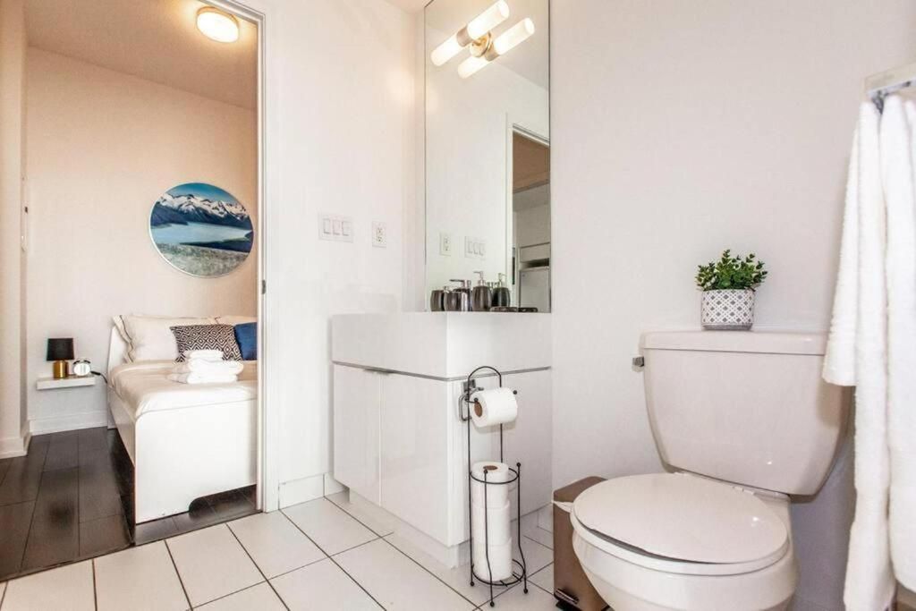 A modern bathroom with a toilet, sink, and mirror. There is a towel rack and a small plant on the sink.