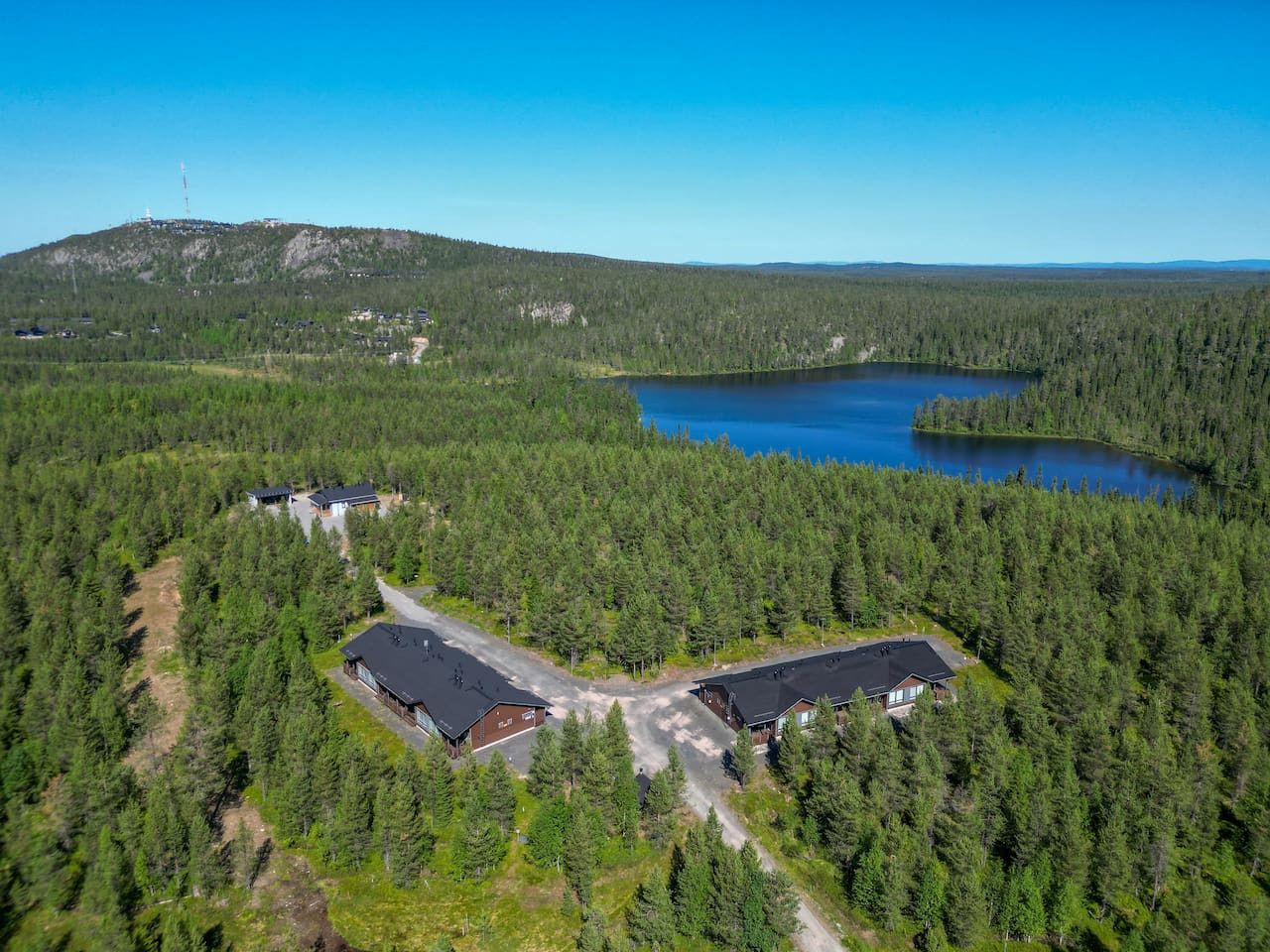 Ilmakuva metsäisestä alueesta, jossa on järvi, useita rakennuksia ja taustalla vuori.