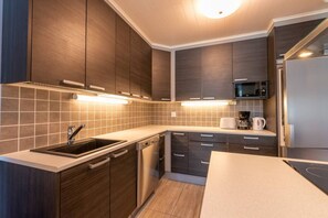 A modern kitchen with dark wood cabinets, a stainless steel sink, and a built-in microwave. - Amazing for outdoors. Incl. cleaning and wifi (Rukatunturi)