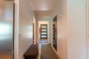 A hallway with a bench, a door with a fire alarm, and a refrigerator. - Amazing for outdoors. Incl. cleaning and wifi (Rukatunturi)