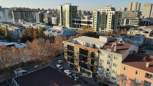A multi-story building with a flat roof, surrounded by other buildings, and a parking area with cars. - New My World Hotel (Istanbul)