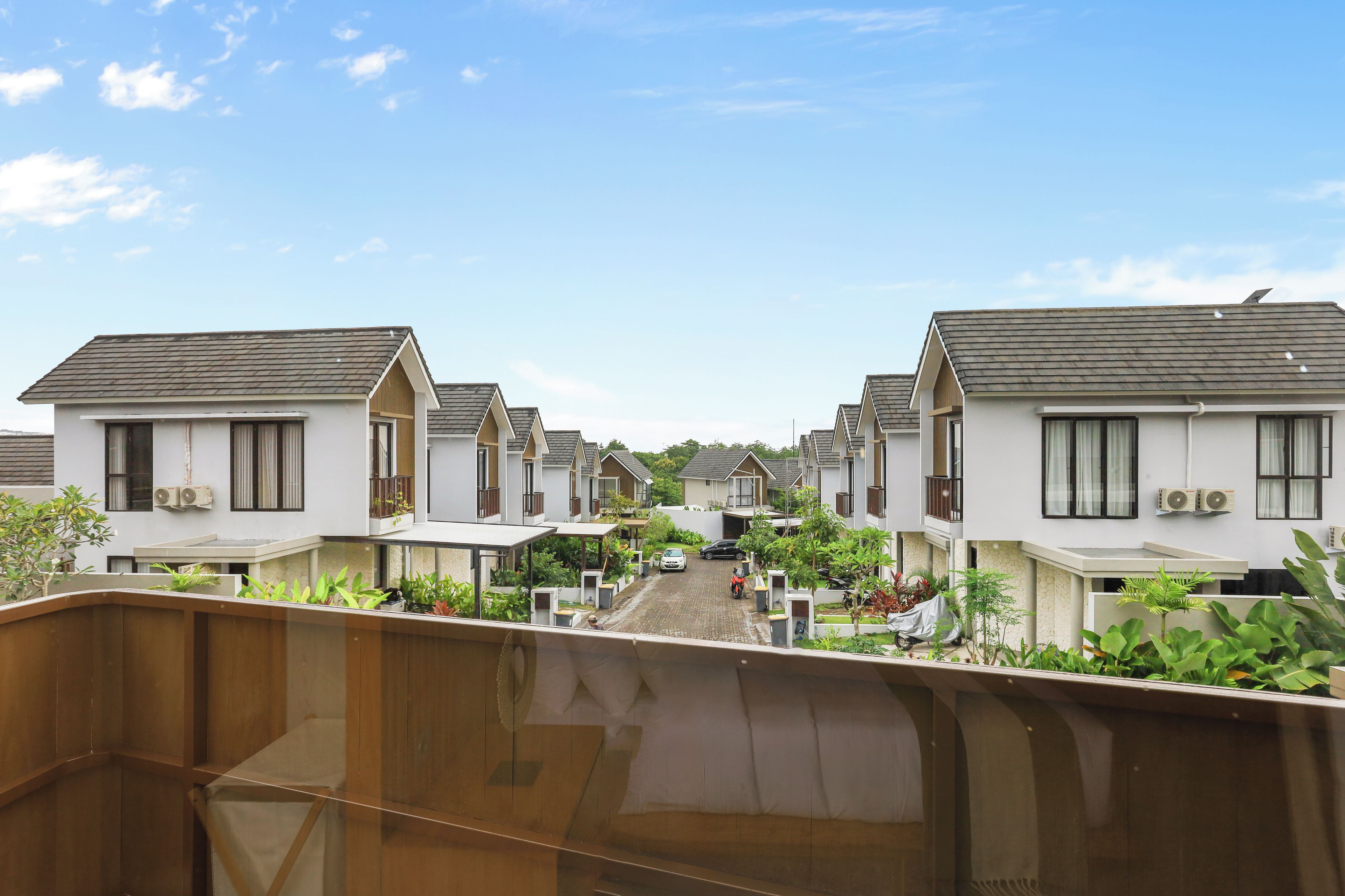 A row of modern, single-story houses with flat roofs, arranged in a straight line down a street.