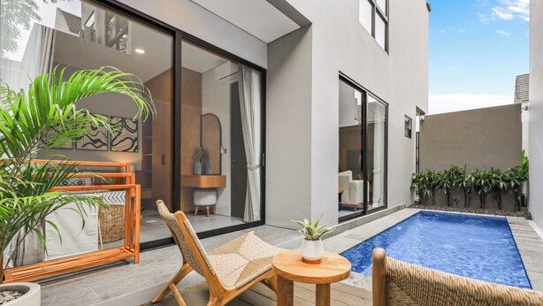 Uma área de estar moderna ao ar livre, com piscina, móveis de vime e plantas em vasos.