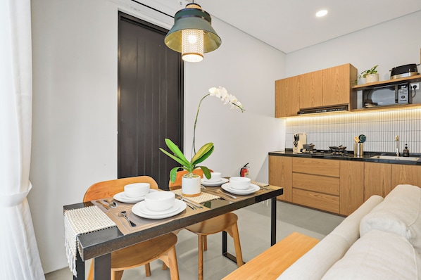 Una cocina moderna con armarios de madera, un microondas y una zona de comedor con una mesa para dos.