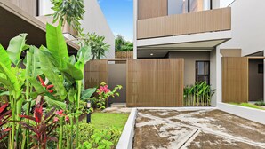 Um pátio moderno com cerca de madeira, plantas em vasos e um caminho de concreto.