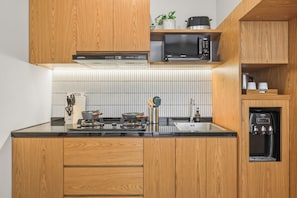 Una cocina moderna con armarios de madera, estufa de acero inoxidable, microondas y dispensador de agua integrado.