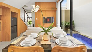 Uma sala de jantar moderna com uma mesa posta para quatro pessoas, uma televisão na parede e vista para o exterior.