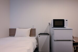 A hotel room with a bed, a microwave, and a refrigerator.