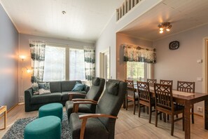 A living room with a sofa, two armchairs, a dining table with chairs, and a staircase leading to an upper level. - Apartment surrounded by the nature, incl. cleaning (Rukatunturi)