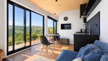 A modern kitchen with a black countertop and a flat-screen TV mounted on the wall.