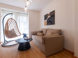 A living room with a hanging chair, a sofa, a round coffee table, and a painting on the wall. - Central two-bedroom apartment (Málaga)
