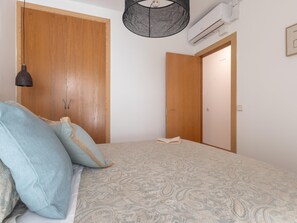 A bedroom with a bed, a hanging light fixture, an air conditioning unit, and a door. - Central two-bedroom apartment (Málaga)