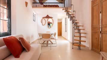 Un interior moderno con un sofá, una mesa de comedor, sillas, una escalera y una puerta de madera grande.