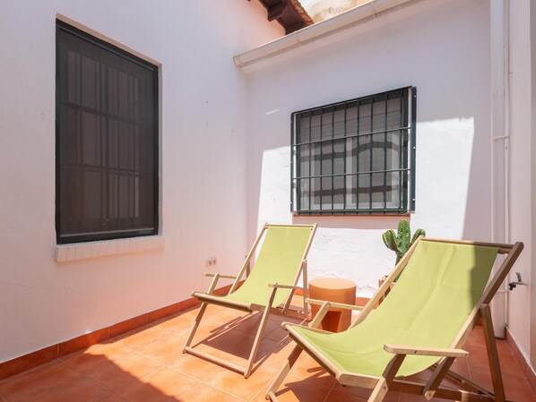 A small patio area with two folding chairs and a cactus plant.