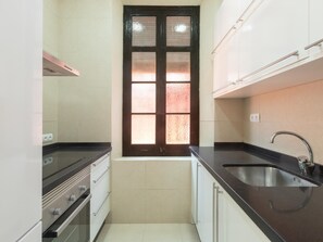 A compact kitchen with a window, stainless steel appliances, and a sink.