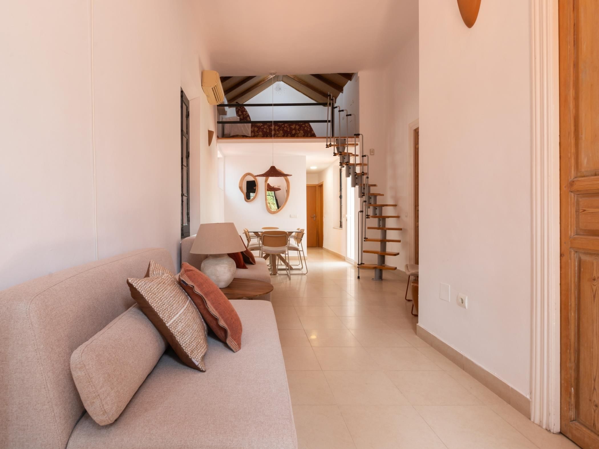 Un interior moderno con un sofá, zona de comedor y una escalera.
