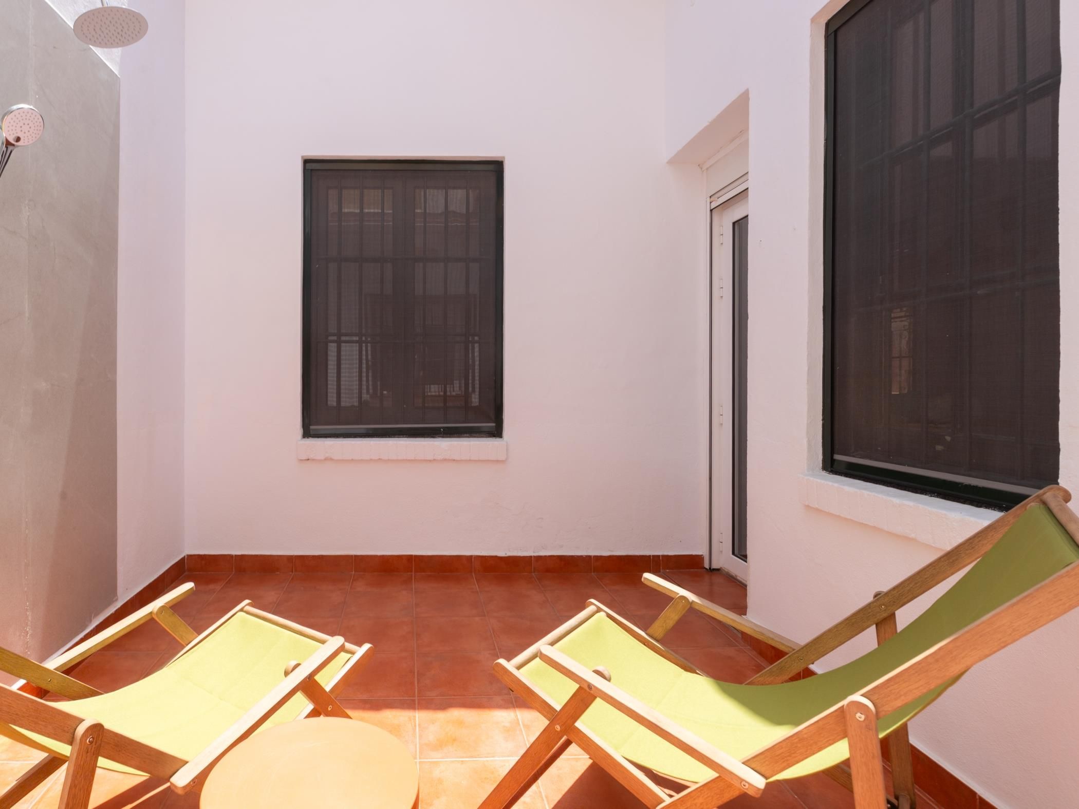 Un piccolo balcone privato con due sedie di legno e una finestra.