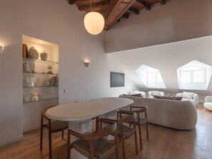 Ein modernes Loft mit Essbereich, einer Sofagarnitur und einem an der Wand montierten Fernseher.