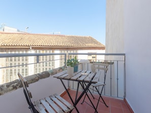 A balcony with a wooden table, two chairs, a potted plant, and a white mug. - Centrally located apartment with a terrace (Málaga)