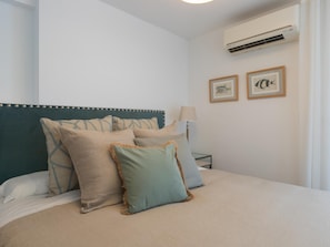 A neatly made bed with a headboard, a bedside lamp, and two framed pictures on the wall. - Centrally located apartment with a terrace (Málaga)