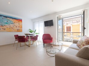 A living room with a sofa, a red chair, a glass table, and a painting on the wall. - Centrally located apartment with a terrace (Málaga)
