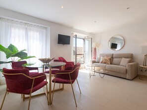 A modern living room with a sofa, red chairs, a glass coffee table, and a large plant. - Centrally located apartment with a terrace (Málaga)