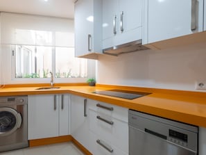 A modern kitchen with white cabinets, a stainless steel dishwasher, and a built-in oven. - Centrally located apartment with a terrace (Málaga)