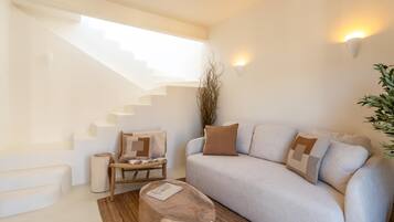 A modern living room with a staircase, a sofa set, a coffee table, and a plant.